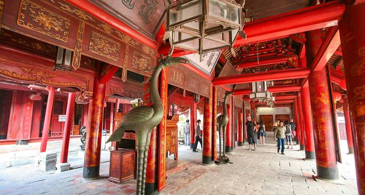 Interieur van traditionele rode tempel met toeristen.