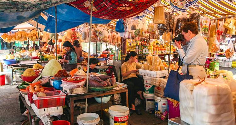 Kleurrijke markt met lokale verkopers en toeristen die foto's maken.