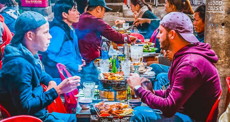 Mensen die eten bij een drukke straatvoedselmarkt.