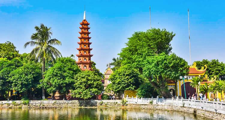 Een pagode omringd door weelderig groen nabij een meer.
