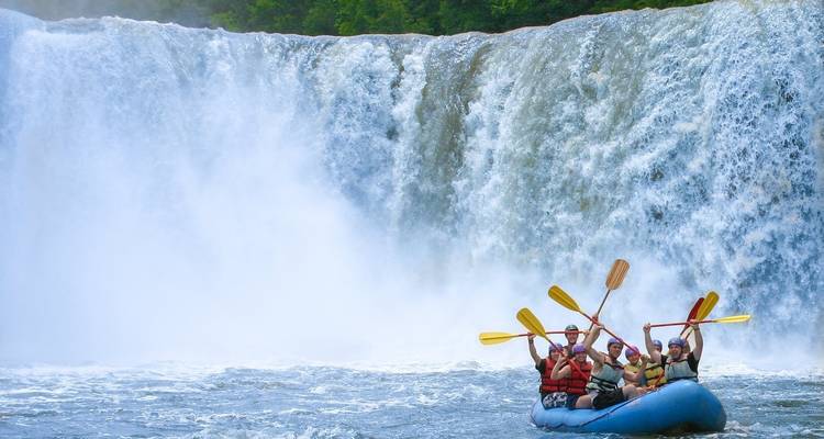 Grupo de personas haciendo rafting cerca de una cascada.
