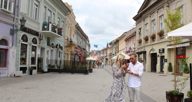 Scène de rue dans un quartier historique avec de vieux bâtiments et un couple qui marche.