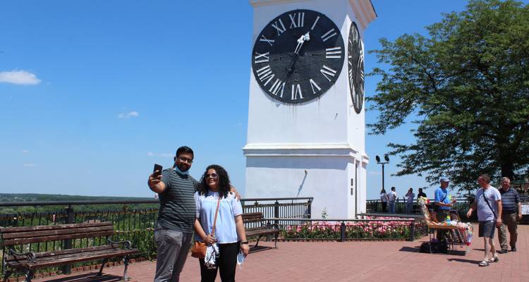Des personnes qui prennent un selfie devant une grande tour d'horloge.