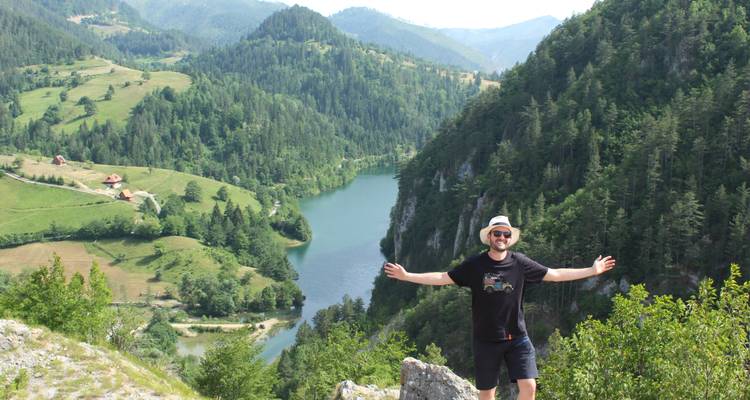 Une personne qui célèbre sur une colline avec une rivière en arrière-plan.