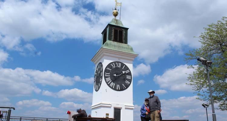 Une grande tour d'horloge contre un ciel bleu avec des gens au premier plan.