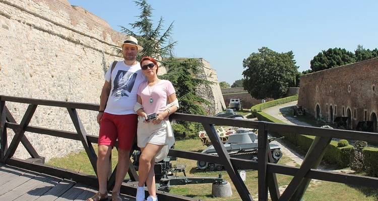 Couple debout sur un pont en bois à l'intérieur d'une forteresse.