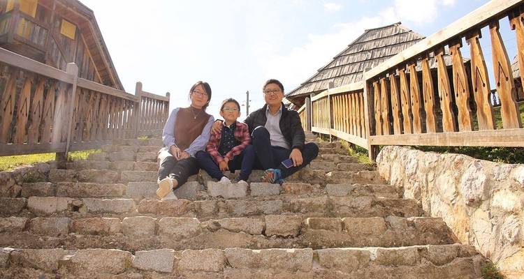 Famille assise sur des marches en pierre à côté d'une architecture en bois.