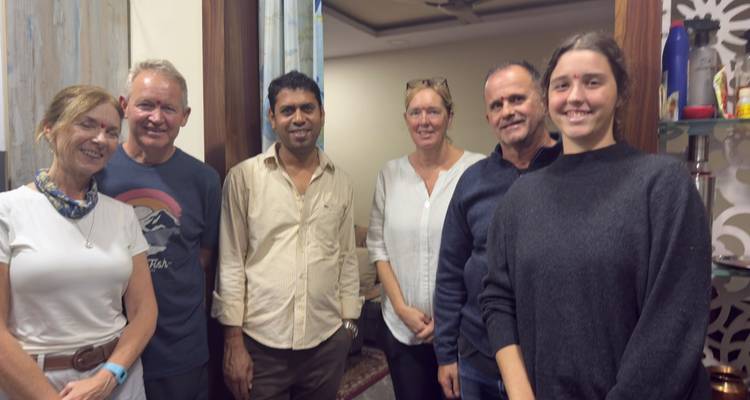 Sechs Personen posieren drinnen in der Nähe eines Spiegels.