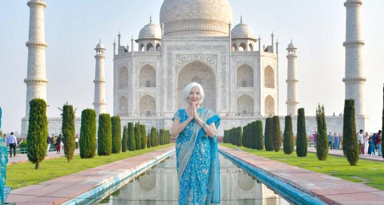 Frau in traditioneller Kleidung betet vor dem Taj Mahal.