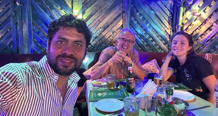 Drei Menschen, die zusammen in einem schwach beleuchteten Restaurant speisen.