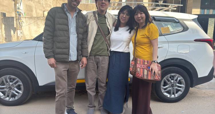 Familie steht vor einem geparkten weißen Auto auf einer Straße.