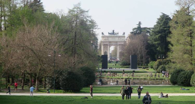 Des gens marchant à travers un parc vers l'Arc de la Paix.