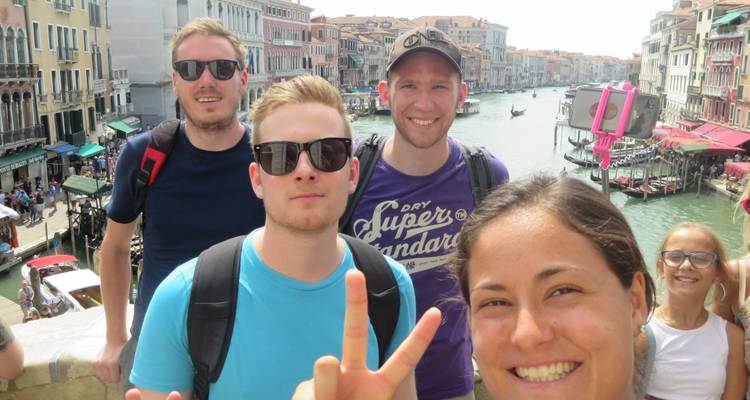 Grupo de personas tomándose una selfie en un puente sobre un canal.