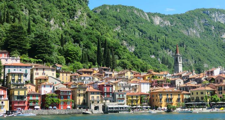 Casas coloridas junto a un lago con montañas al fondo.