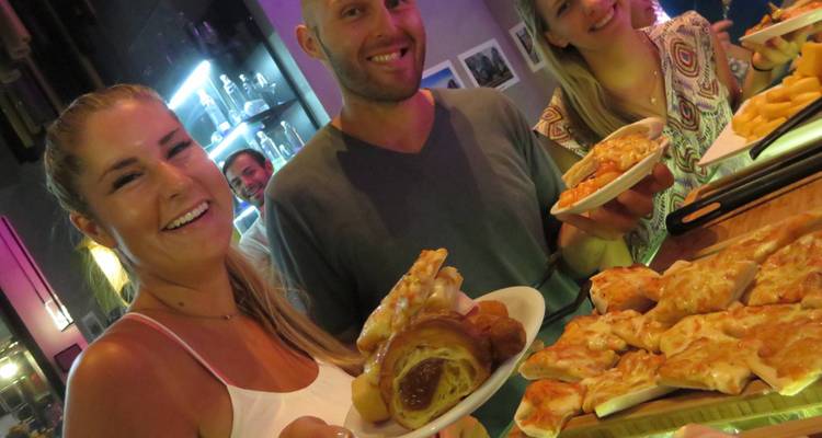 Grupo de personas sosteniendo platos de comida en un ambiente animado.