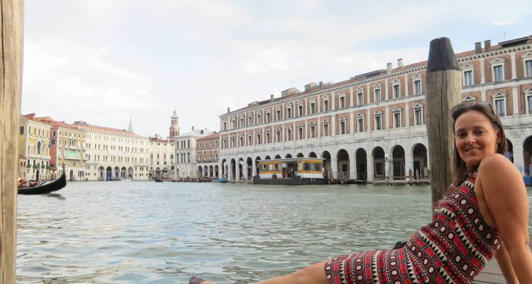 Persona sentada junto a un canal con góndolas.