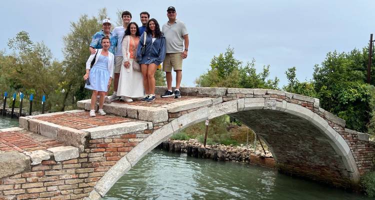 Groupe de personnes posant sur un petit pont arqué au-dessus de l'eau.