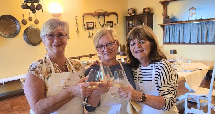 Trois femmes trinquant avec du vin à l'intérieur, portant des tabliers.