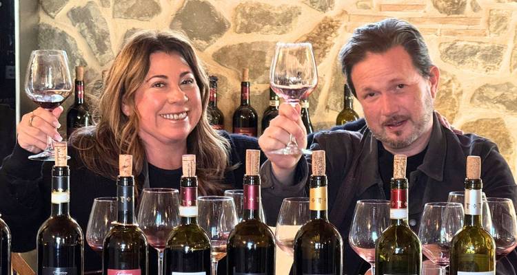 Homme et femme trinquant avec du vin dans une salle de dégustation.