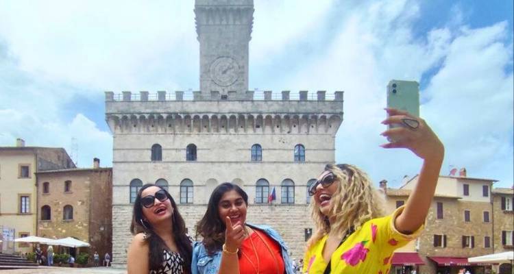 Trois femmes prenant un selfie devant un bâtiment historique.