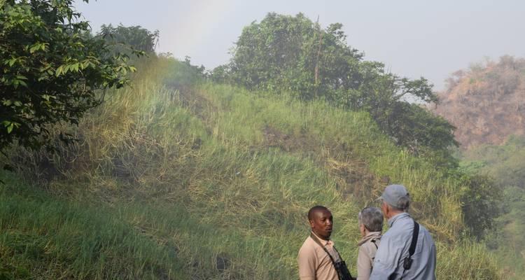 Een groep mensen met weelderig groen en een vage regenboog.