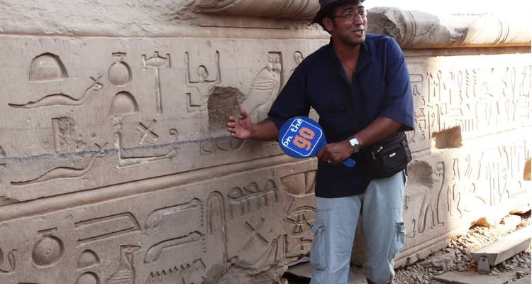 Persona explicando jeroglíficos en una pared de piedra.