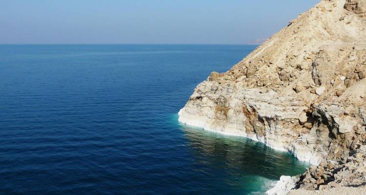 Landschap van een rotsachtige kustlijn met helder blauw water van de Dode Zee.