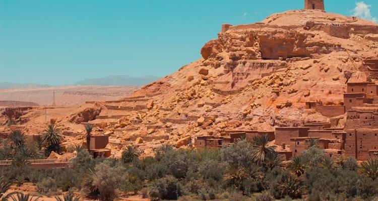 Colline avec une forteresse historique surplombant une oasis verte.