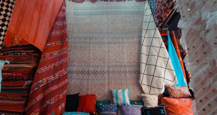 Des textiles colorés suspendus et empilés dans un étalage de marché.
