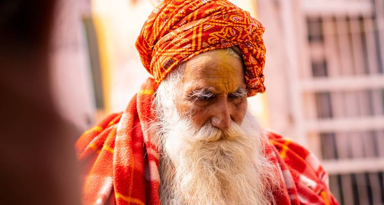 Elderly person in traditional attire with a contemplative expression.