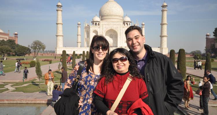 Des touristes souriants devant le Taj Mahal par une journée claire.