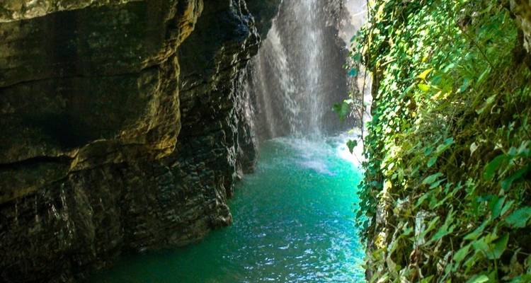 Cascada en un cañón estrecho con follaje verde.