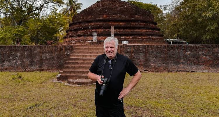 A man posing in front of an ancient brick structure.