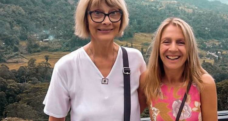 Two women smiling with a scenic view in the background.