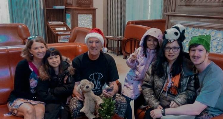 Family posing indoors with Christmas decorations.