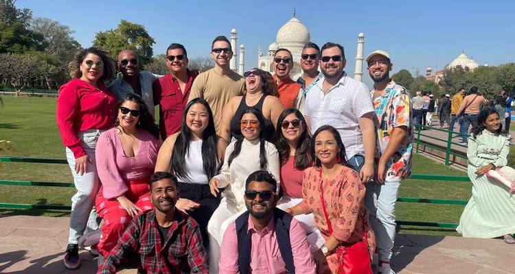 Groepsfoto van mensen met de Taj Mahal op de achtergrond.