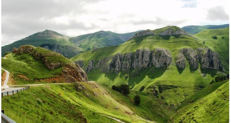 Exuberantes colinas y montañas verdes bajo un cielo nublado.