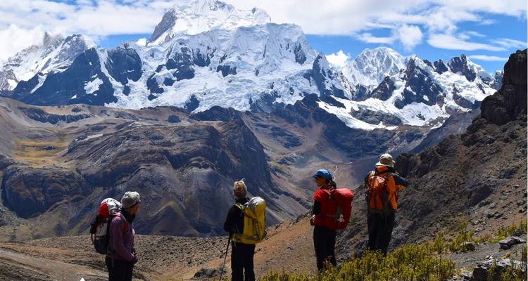 Four hikers admiring the view of snowy mountains.
