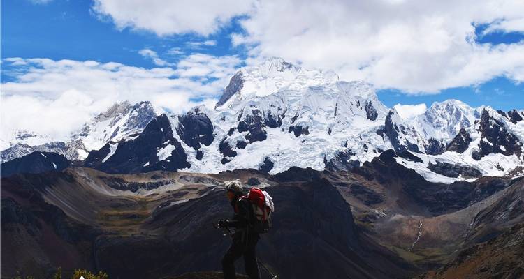 A hiker silhouetted against a backdrop of snow-covered mountains.
