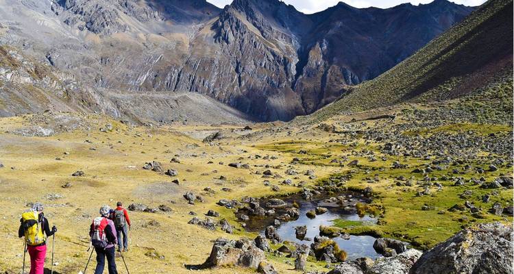 Hikers walking in a mountainous landscape with rocks and hills.