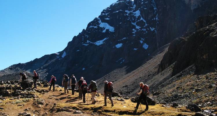 Group of hikers on a mountain trail with a view of the peaks.
