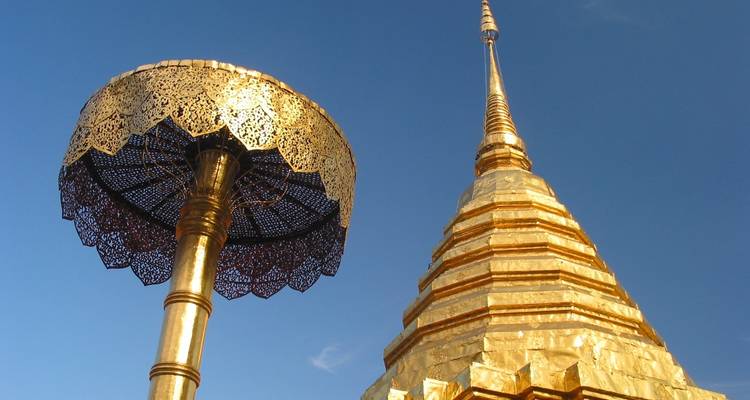 Golden pagoda and ornate umbrella against a blue sky.