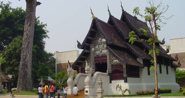 Traditional Thai temple with intricate design and people in the foreground.