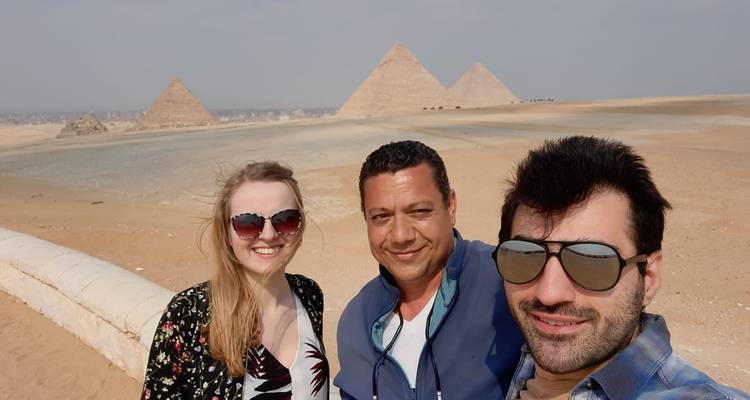 Drei Menschen posieren vor Pyramiden.