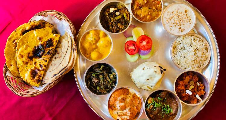 Traditional Indian thali with various dishes on a silver platter.