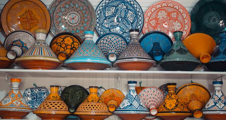 Estantes ordenados apilados con coloridas ollas de tajine pintadas a mano en una tienda de cerámica