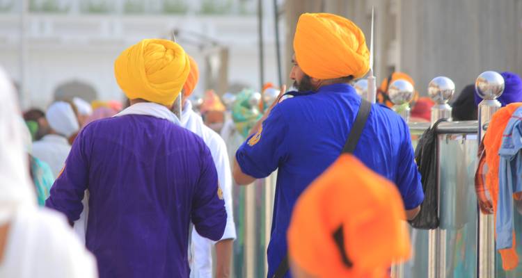 Des hommes en tenue traditionnelle sikh marchant parmi une foule.