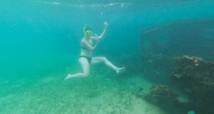 Persona haciendo snorkel bajo el agua cerca de un naufragio.