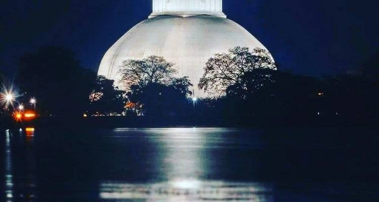 Stupa oder große Kuppelstruktur, nachts beleuchtet.