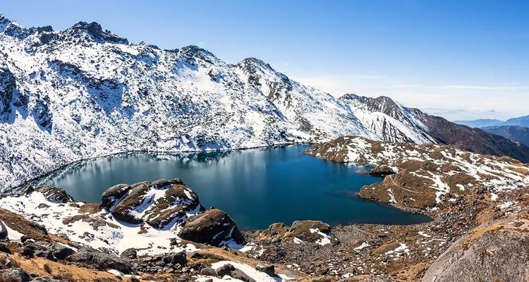 Des montagnes enneigées entourant un lac bleu serein.